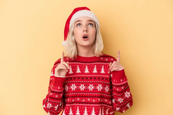年轻的高加索女人在黄色背景下闭着嘴庆祝圣诞节 — 图库照片