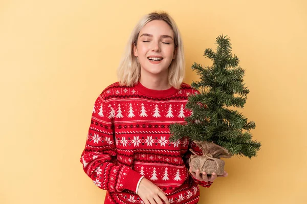 若いですCaucasian女性を保持少しクリスマスツリー孤立した上黄色の背景笑いと楽しみを持って — ストック写真
