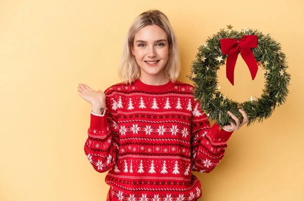 Young Caucasian Woman Holding Christmas Wreath Isolated Yellow Background Showing —  Fotos de Stock