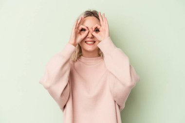 Genç beyaz kadın, yeşil arka planda izole edilmiş. Heyecanlı. Tamam, dikkatli ol..