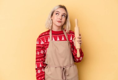 Kafkasyalı genç fırıncı kadın Noel için kurabiye yapıyor sarı arka planda izole edilmiş hedeflere ve amaçlara ulaşma hayali kuruyor.