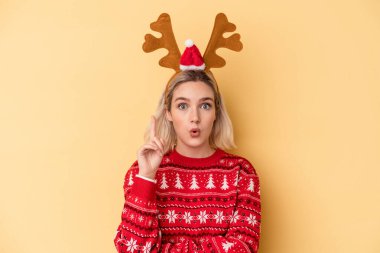 Sarı arka planda izole edilmiş, Noel geyiği şapkası takan beyaz bir kadın harika bir fikre sahip, yaratıcılık kavramı..