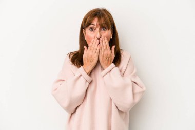 Beyaz arka planda izole edilmiş orta yaşlı beyaz kadın şok olmuş, ağzı ellerle kaplanmış, yeni bir şey keşfetmeye hevesli..