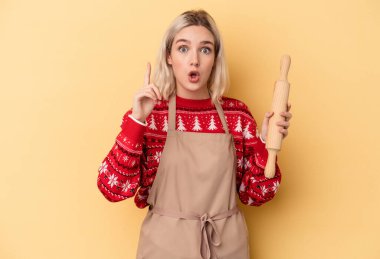 Kafkasyalı genç fırıncı kadın Noel için kurabiye yapıyor sarı arka planda izole edilmiş bir şekilde bir fikri, ilham verici bir konsepti var..