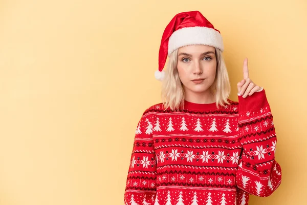 年轻的高加索女人用手指在黄色背景下庆祝圣诞节 — 图库照片
