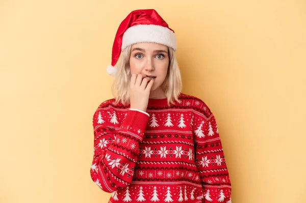 若いです白人女性祝うクリスマスは黄色の背景に隔離された爪をかむ 神経と非常に不安 — ストック写真