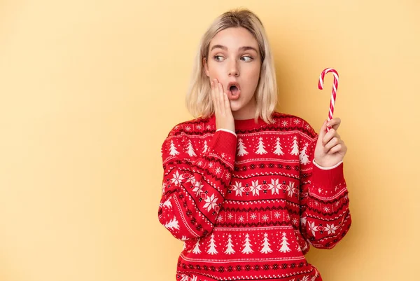 Mladá Běloška Drží Vánoční Hůl Izolované Žlutém Pozadí Říká Tajnou — Stock fotografie