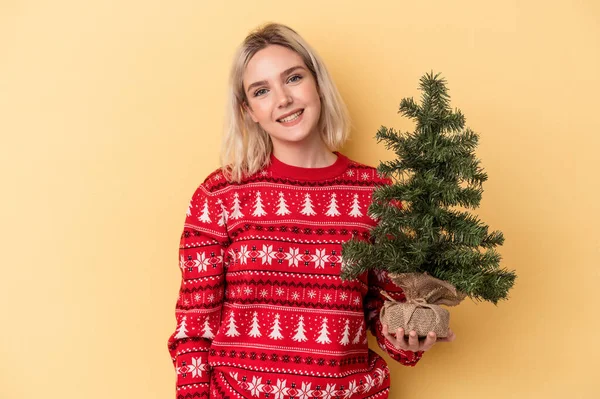 Mladá Běloška Drží Malý Vánoční Stromek Izolovaný Žlutém Pozadí Šťastný — Stock fotografie
