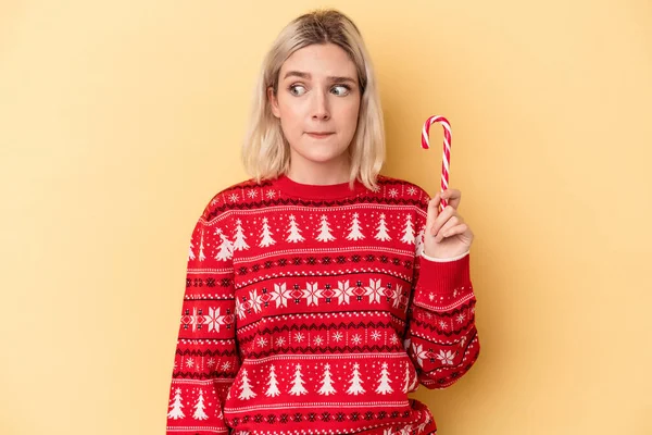 Giovane Donna Caucasica Possesso Bastone Natale Isolato Sfondo Giallo Confuso — Foto Stock