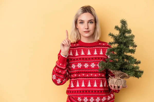 Junge Kaukasische Frau Mit Einem Kleinen Weihnachtsbaum Auf Gelbem Hintergrund — Stockfoto