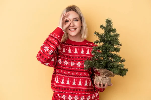 Mladá Běloška Žena Drží Malý Vánoční Stromek Izolované Žlutém Pozadí — Stock fotografie