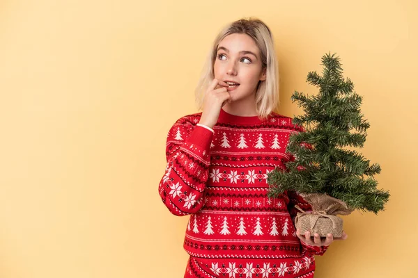 Jovem Caucasiana Segurando Uma Pequena Árvore Natal Isolada Fundo Amarelo — Fotografia de Stock