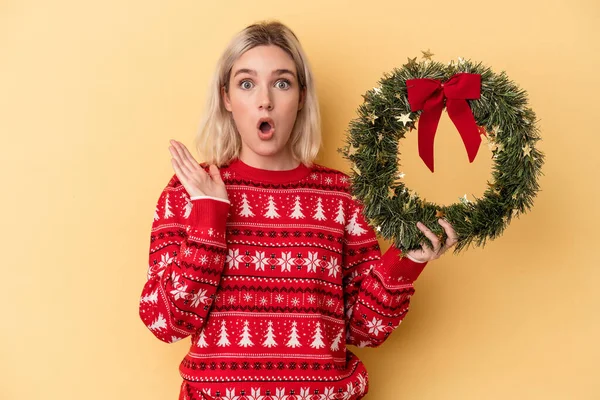 Young Caucasian Woman Holding Christmas Wreath Isolated Yellow Background Surprised — Foto Stock