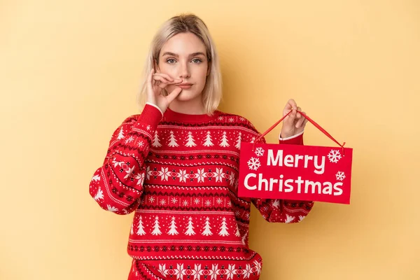 Mladá Běloška Drží Veselé Vánoční Plakát Izolované Žlutém Pozadí Prsty — Stock fotografie