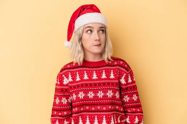 若いです白人女性を祝いますクリスマスは黄色の背景に孤立混乱しました 疑いと不確定な感じ — ストック写真