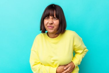 Mavi arka planda karaciğer ağrısı ve mide ağrısı çeken genç bir ırk kadını..