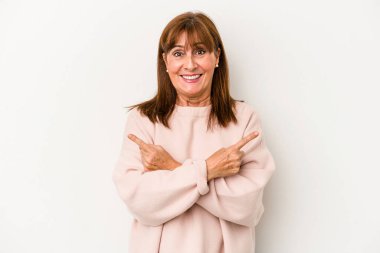 Beyaz arka planda izole edilmiş orta yaşlı beyaz kadın iki seçenek arasında seçim yapmaya çalışıyor..