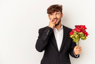 Beyaz arka planda izole edilmiş gül buketi tutan genç bir ırk. Bir şeyin fotokopi alanına baktığını düşünerek rahatlıyor..