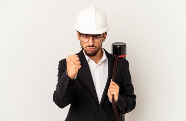 Gri arka planda izole edilmiş kask takan genç mimar kameraya yumruk gösteriyor, agresif yüz ifadesi var..
