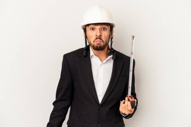 Kask takan ve takan genç mimar gri arka planda izole edilmiş taksimetre omuz silkiyor ve gözleri açık..