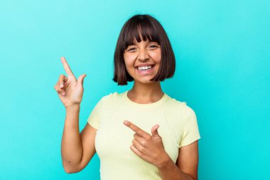 Mavi arka planda izole edilmiş genç melez bir kadın işaret fişeklerini göstererek heyecanlanıyor..