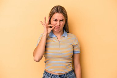 Sarı arka planda izole edilmiş genç, beyaz bir kadın parmakları dudaklarında bir sır saklıyor..