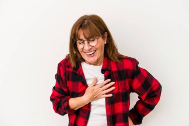 Beyaz arka planda soyutlanmış orta yaşlı beyaz kadın gülüyor, elini kalbe atıyor, mutluluk kavramını koruyor..