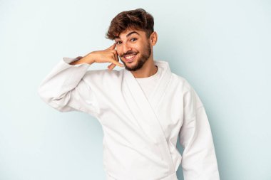 Mavi arka planda karate yapan genç melez, parmakları olan bir cep telefonu hareketini gösteriyor..