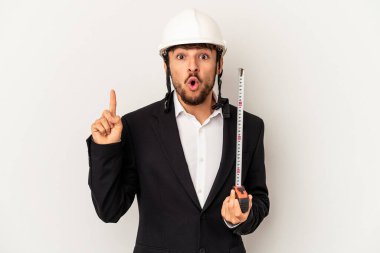 Miğfer takan ve taksimetre tutan genç mimar gri arka planda harika bir fikre, yaratıcılık kavramına sahip..