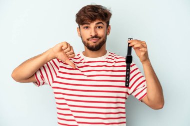 Mavi arka planda izole edilmiş bir kol saati tutan melez genç bir adam hoşlanmadığı bir jest gösteriyor. Anlaşmazlık konsepti.