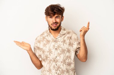 Genç melez adam gri arka planda izole edilmiş ve elinde bir ürün var..