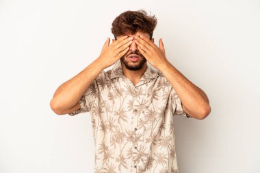 Genç melez adam, gri arka planda izole edilmiş elleri olan gözleri kapamaktan korkuyor..