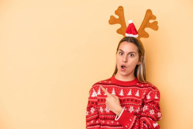 Sarı arka planda izole edilmiş, Noel geyiği şapkası takan beyaz bir kadın.