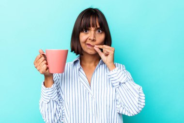 Mavi arka planda pembe kupa tutan genç bir ırk kadını. Parmakları dudaklarında bir sır saklıyor..