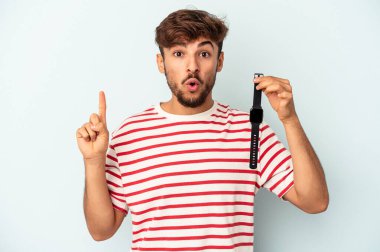 Mavi arka planda izole edilmiş bir kol saati tutan genç melez adamın harika bir fikri var, yaratıcılık kavramı..