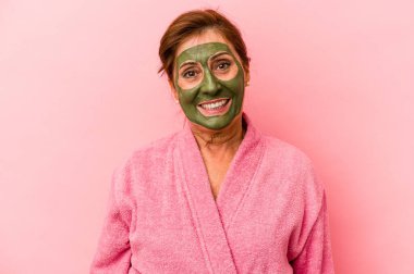 Middle age caucasian woman wearing a facial mask isolated on pink background happy, smiling and cheerful.