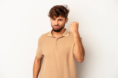Genç melez adam gri arka planda izole edilmiş kameraya yumruk, agresif yüz ifadesi gösteriyor..