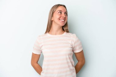 Genç beyaz kadın mavi arka planda izole edilmiş rahat ve mutlu bir şekilde gülüyor, boynunda dişlerini gösteriyor..