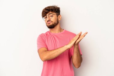 Genç melez adam gri arka planda izole edilmiş enerjik ve rahat hissediyor, ellerini ovuşturuyor kendinden emin..