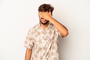 Gri arka planda soyutlanmış genç bir ırk. Gözleri ellerle kaplıyor. Gülümsüyor ve bir sürpriz bekliyor..