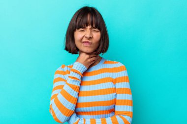 Mavi arka planda izole edilmiş genç melez kadın virüs ya da enfeksiyon yüzünden boğazında ağrı hissediyor..