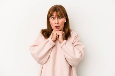 Beyaz arka planda izole edilmiş orta yaşlı beyaz bir kadın şans için dua ediyor, şaşırıyor ve ağzını açıyor..