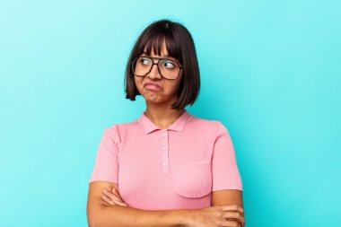 Mavi arka planda izole edilmiş genç melez kadın hedeflerine ve amaçlarına ulaşma hayali kuruyor.