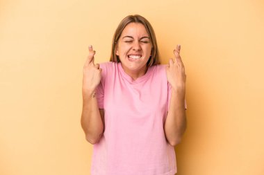 Sarı arka planda izole edilmiş beyaz bir kadın şans dilemek için şans diliyor.