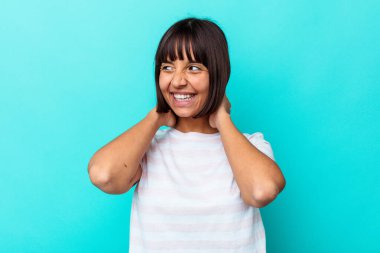 Genç melez kadın mavi arka planda izole edilmiş kendinden emin, elleri başının arkasında..