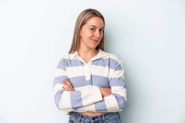 Mavi arka planda izole edilmiş genç beyaz kadın alaycı bir ifadeyle kameraya bakarken mutsuz oluyor..