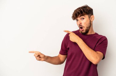 Gri arka planda izole edilmiş genç melez adam işaret parmağıyla fotokopi alanını işaret ederek heyecan ve arzuyu ifade ediyor..