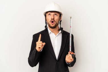 Miğfer takan ve taksimetre tutan genç bir mimar gri arka planda, ağzı açık, üst tarafı işaret ediyor..