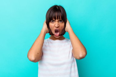 Genç melez kadın, mavi arka planda izole edilmiş öfkeyle bağırıyor..
