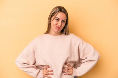 Sarı arka planda soyutlanmış beyaz bir kadın üzgün, ciddi bir yüz, mutsuz ve hoşnutsuz.